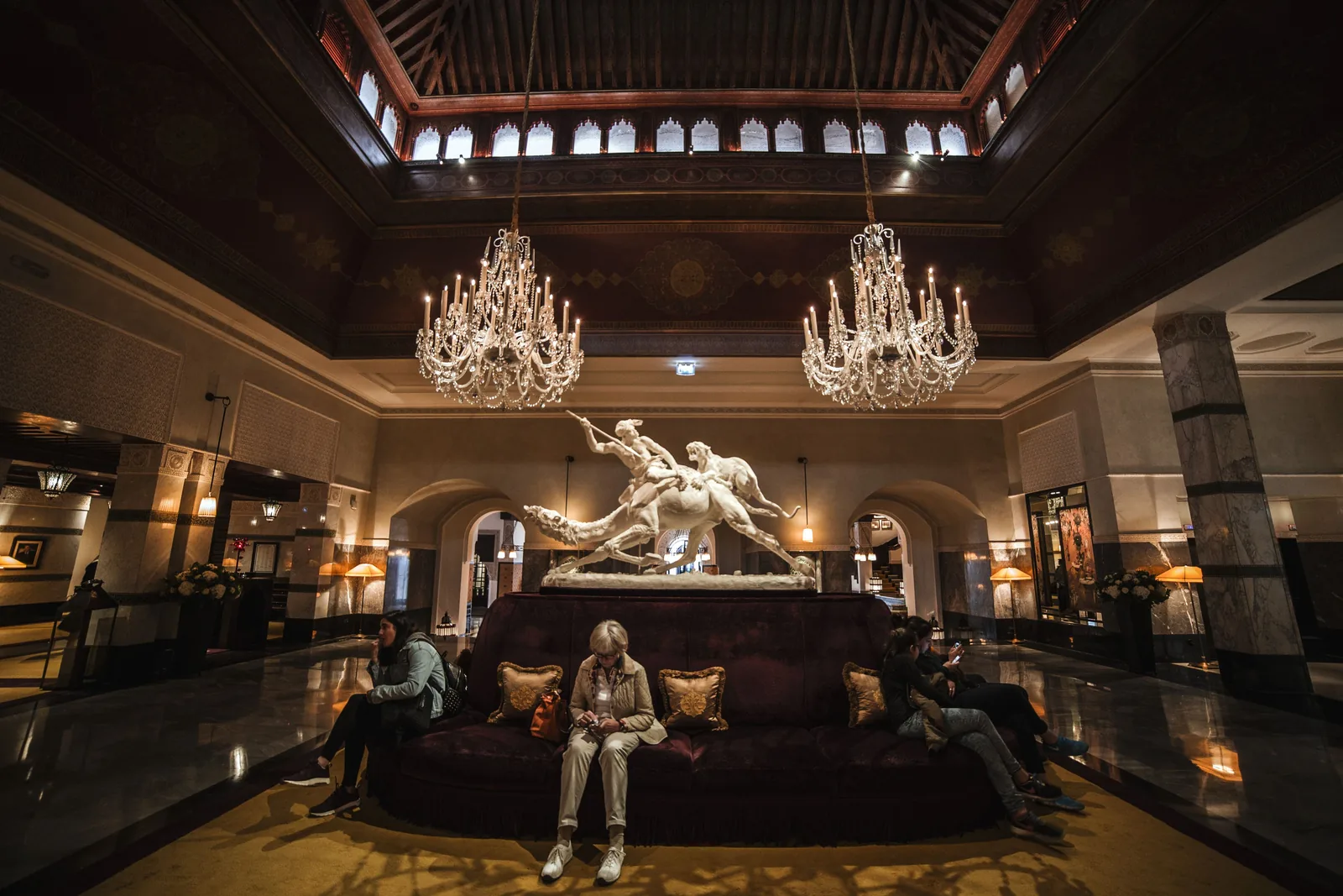 A grand hotel lobby with chandeliers and low seating