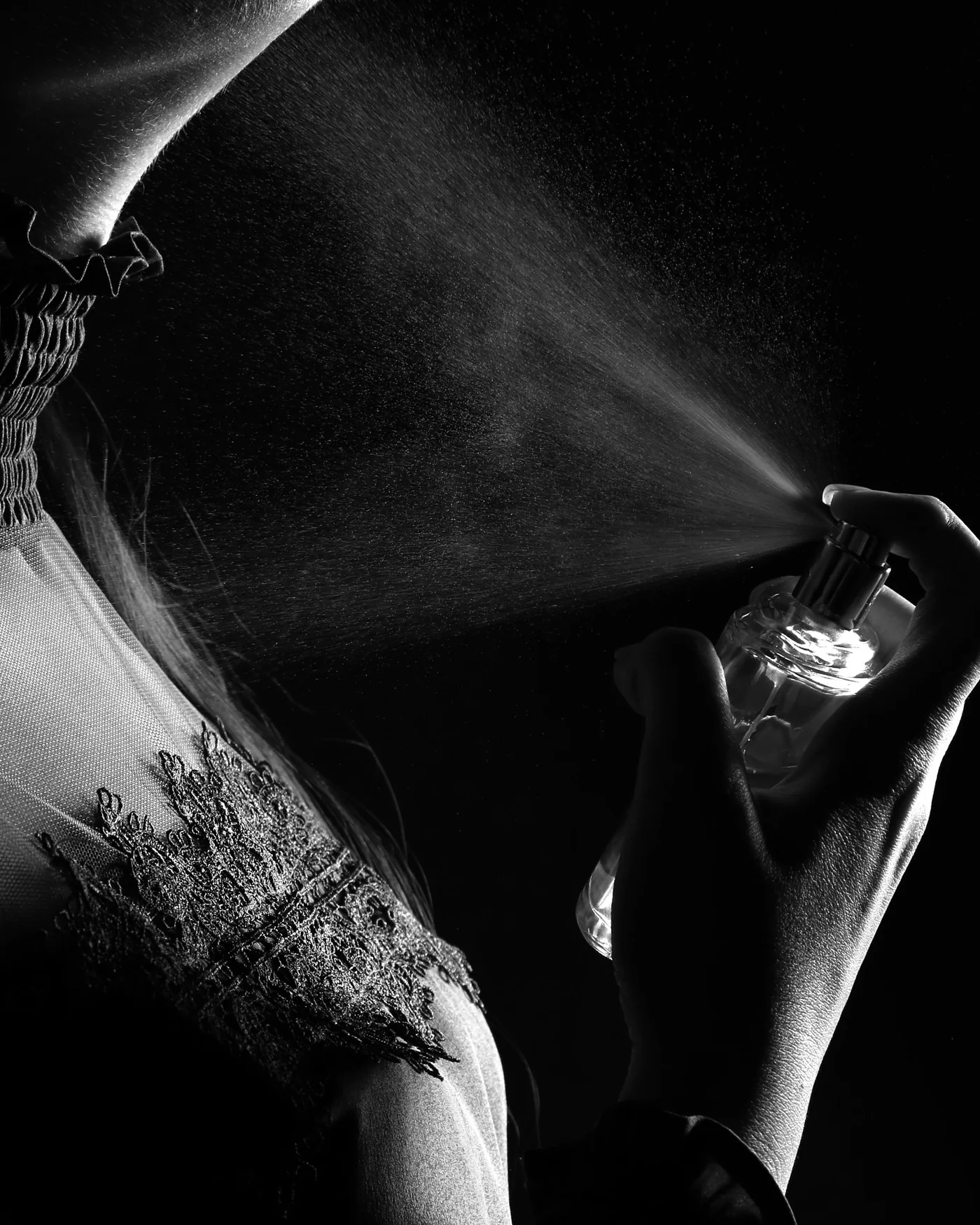 Fragrance being sprayed onto the neck, in black and white